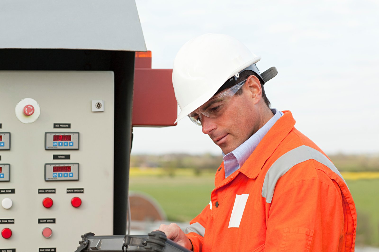 Engineer analyzing data on a machinery control panel outdoors